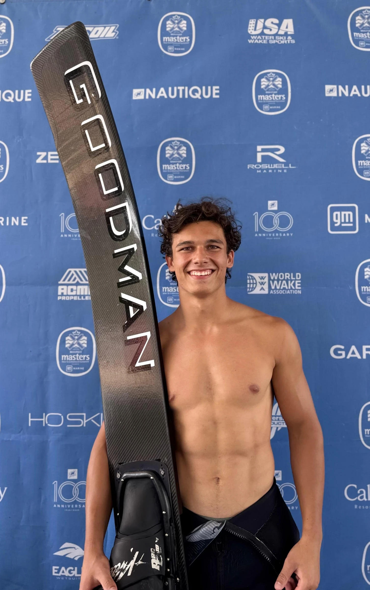 Tim Wild vor ein Sponsorenwand mit seinem Sprungski